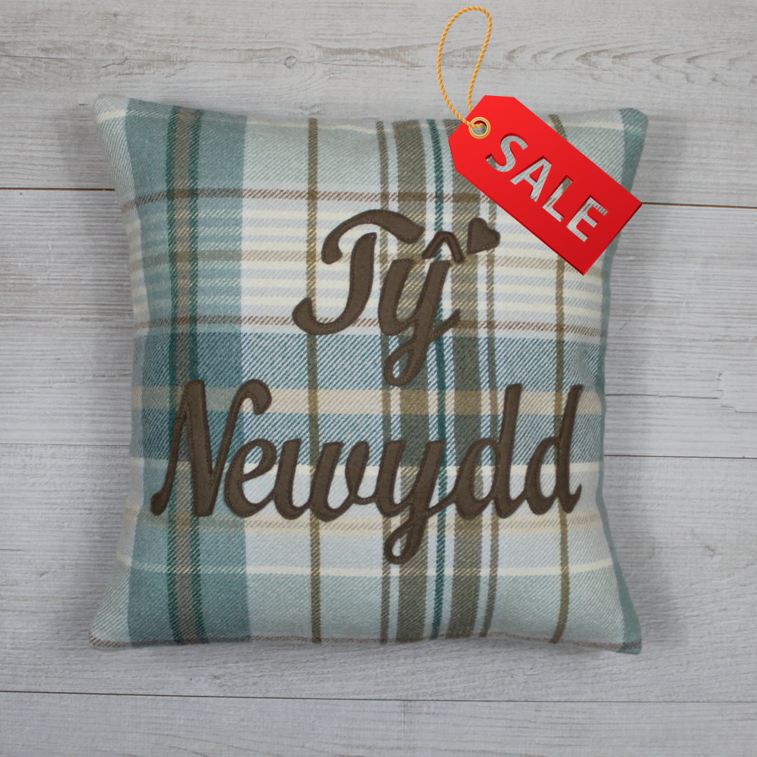 Plaid pillow with 'Ty Newydd' text 
